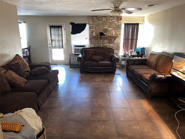 tiled living room featuring cooling unit, ceiling fan, a fireplace, and a textured ceiling