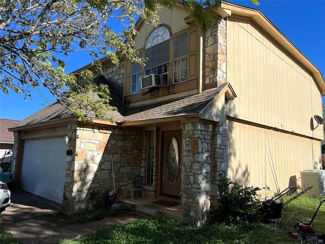 view of front facade featuring cooling unit, a garage, and central air condition unit