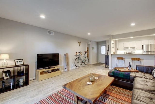 living room with baseboards, light wood finished floors, visible vents, and recessed lighting