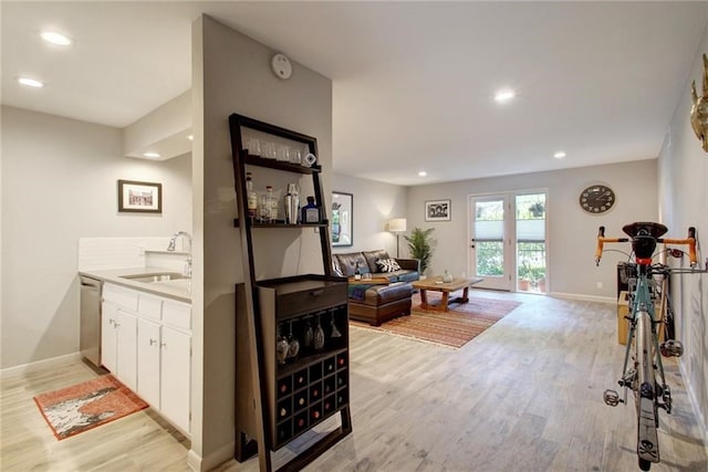 interior space featuring recessed lighting, stainless steel dishwasher, a sink, light wood-type flooring, and baseboards