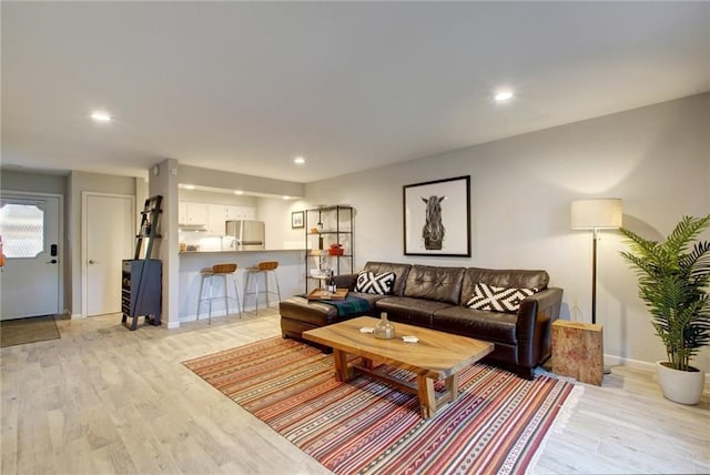 living area with light wood-type flooring, baseboards, and recessed lighting