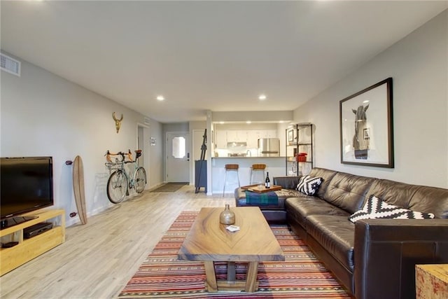 living room featuring light wood-type flooring, visible vents, and recessed lighting