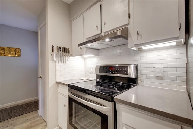 kitchen with light wood finished floors, decorative backsplash, white cabinetry, stainless steel range with electric stovetop, and under cabinet range hood