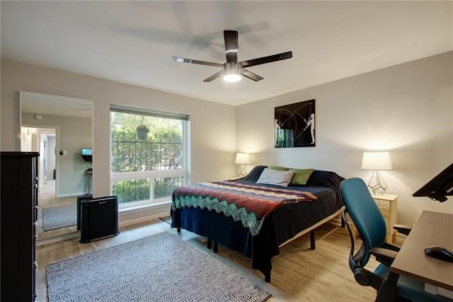 bedroom with light wood-type flooring, ceiling fan, and baseboards