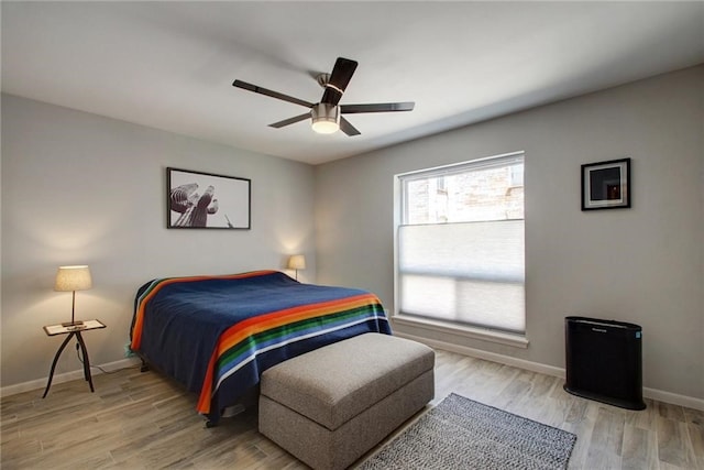 bedroom featuring a ceiling fan, baseboards, and wood finished floors