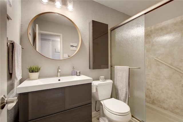 bathroom featuring a textured wall, a stall shower, vanity, and toilet