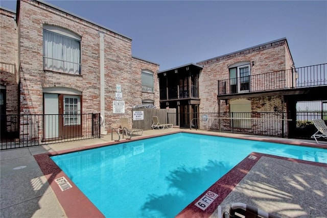 community pool with fence and a patio