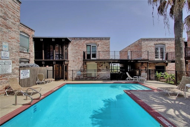 community pool with a patio and fence