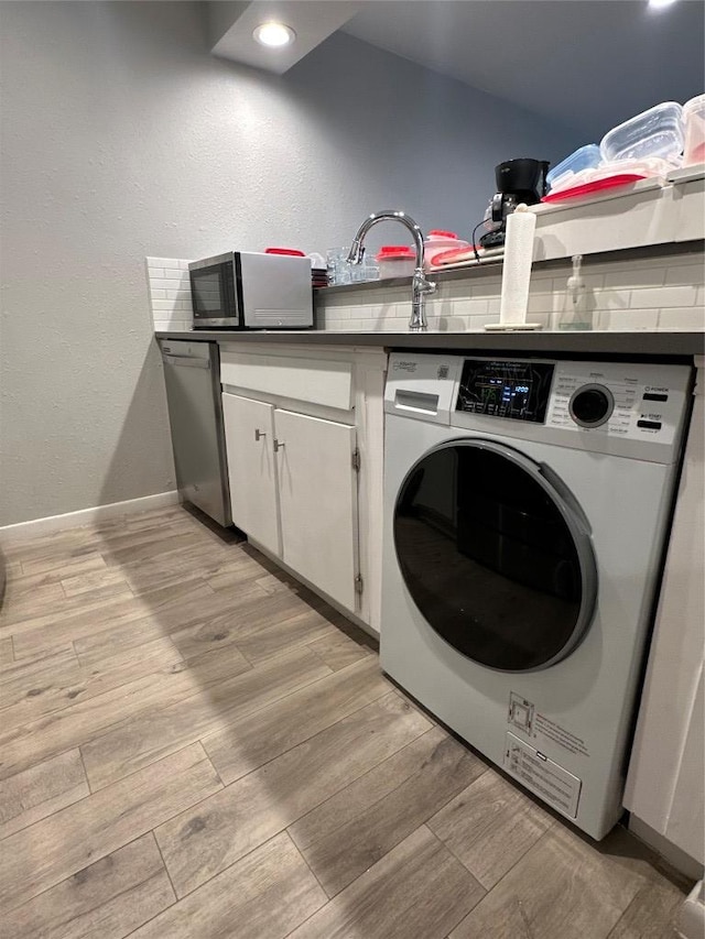 laundry room featuring light wood finished floors, cabinet space, washer / dryer, and baseboards