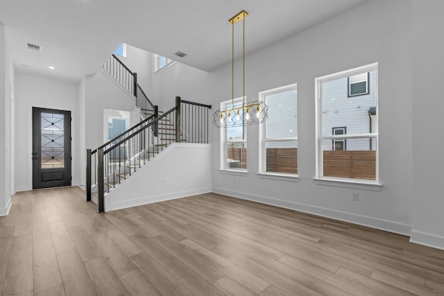 interior space featuring baseboards, a chandelier, stairway, a high ceiling, and wood finished floors