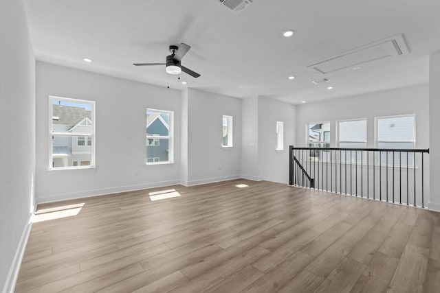 spare room with visible vents, light wood finished floors, baseboards, attic access, and recessed lighting