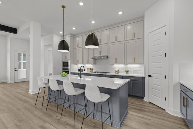 6508 Cowman Way, Austin, TX 78747 - kitchen with a sink, under cabinet range hood, backsplash, appliances with stainless steel finishes, and light wood finished floors