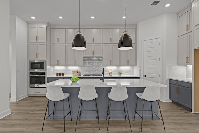 6508 Cowman Way, Austin, TX 78747 - kitchen with stainless steel appliances, under cabinet range hood, decorative backsplash, light countertops, and recessed lighting