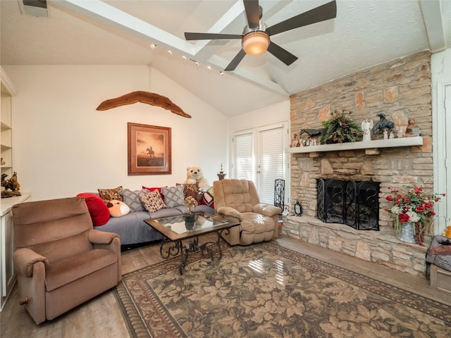 living room with ceiling fan, a fireplace, vaulted ceiling, and light hardwood / wood-style flooring