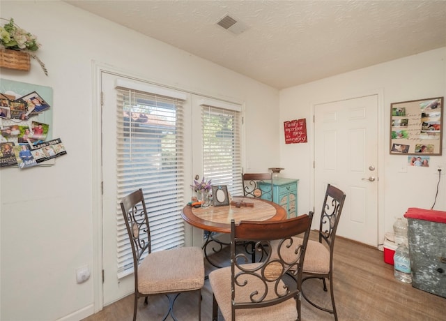 dining space featuring a textured ceiling and hardwood / wood-style floors