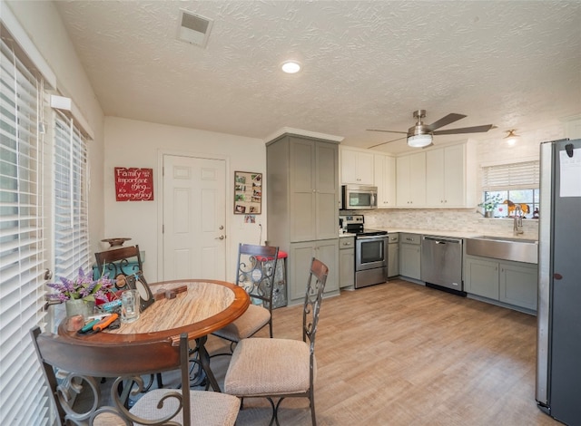 dining area featuring light wood-type flooring, ceiling fan, a textured ceiling, and sink