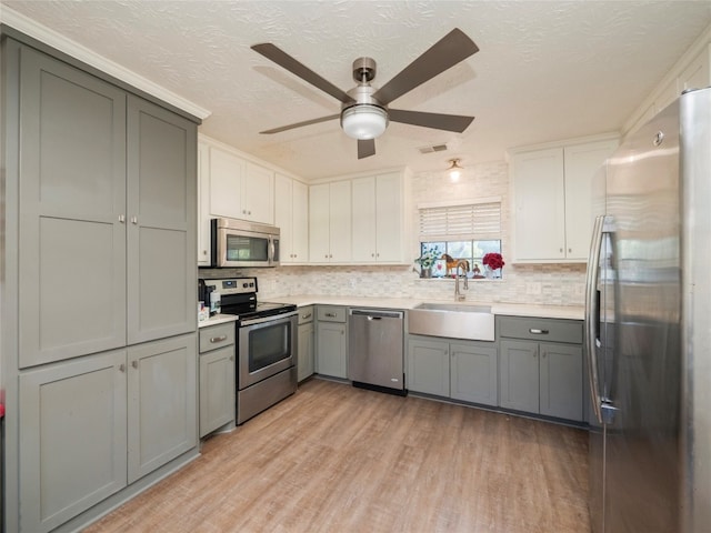 kitchen featuring gray cabinets, stainless steel appliances, ceiling fan, light hardwood / wood-style flooring, and sink