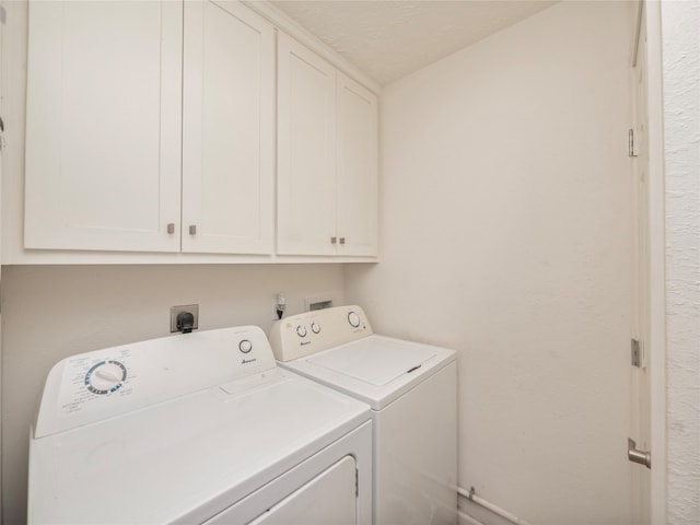 laundry room with a textured ceiling, washing machine and clothes dryer, and cabinets