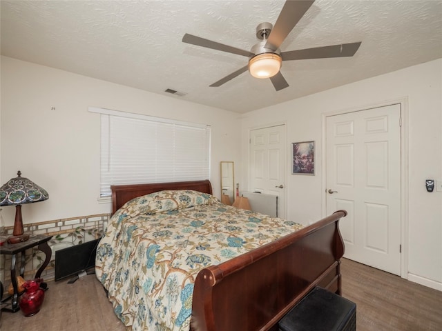 bedroom featuring ceiling fan, a textured ceiling, and dark hardwood / wood-style flooring