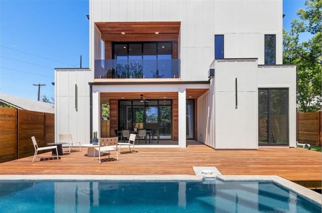 rear view of property featuring ceiling fan and a pool side deck