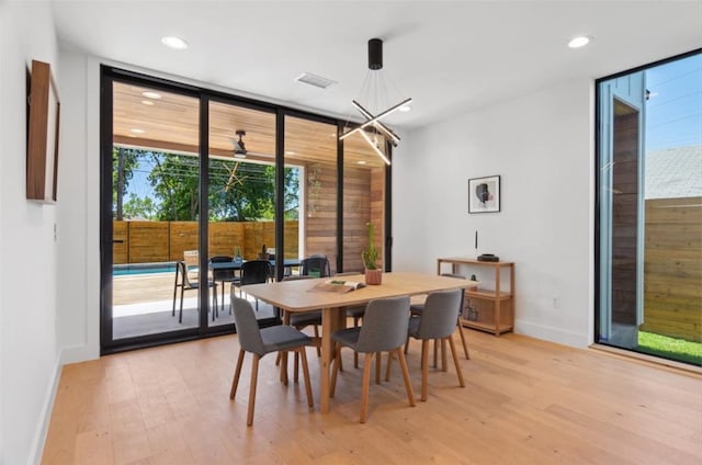 dining room featuring light wood-type flooring, ceiling fan, and expansive windows