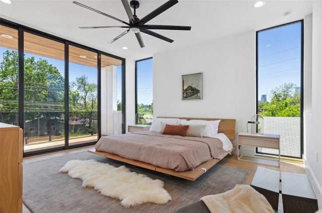 bedroom with ceiling fan, hardwood / wood-style flooring, a wall of windows, and access to exterior