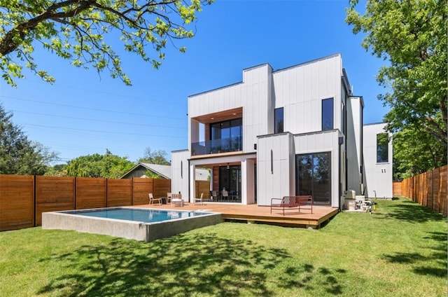 back of property with a balcony, a deck, and a yard