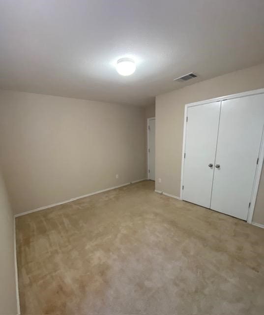 unfurnished bedroom featuring light colored carpet and a closet