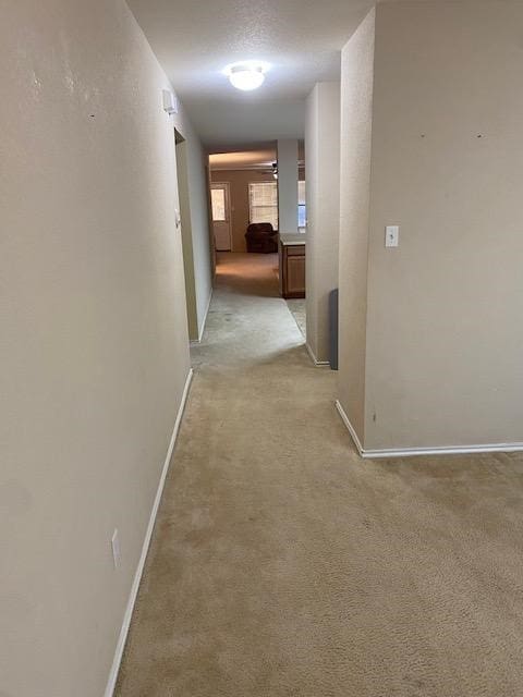 hall with light carpet and a textured ceiling