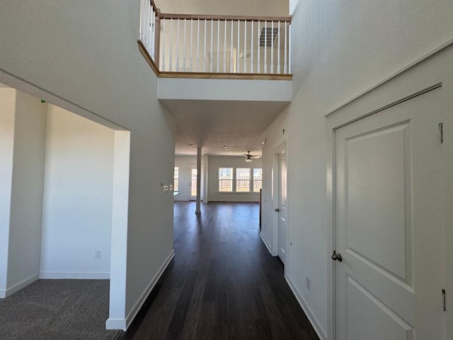 hall featuring a high ceiling and dark wood-type flooring