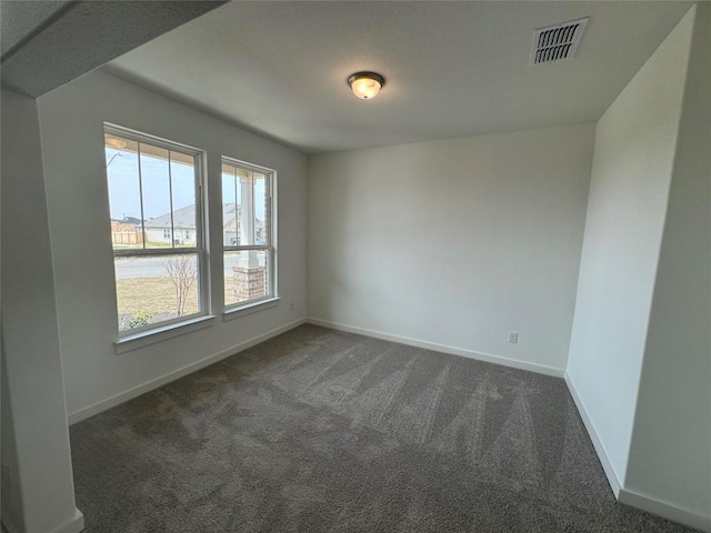 unfurnished room with dark carpet, visible vents, and baseboards