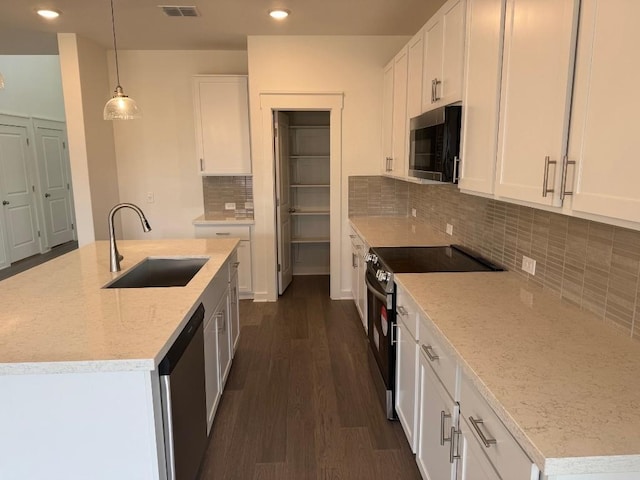 kitchen with dark wood-style flooring, stainless steel appliances, white cabinetry, a sink, and recessed lighting