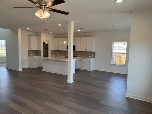 kitchen featuring tasteful backsplash, dark wood-style flooring, light countertops, and a sink