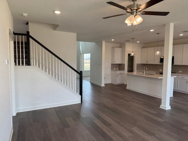 unfurnished living room with baseboards, stairway, dark wood finished floors, and a ceiling fan