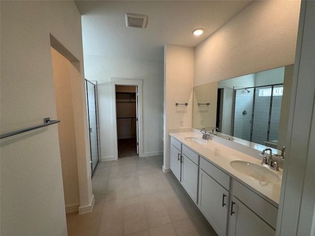 full bath with a walk in closet, double vanity, visible vents, a sink, and a shower stall