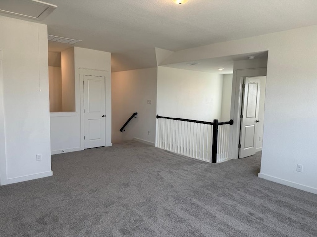 carpeted spare room with attic access and baseboards