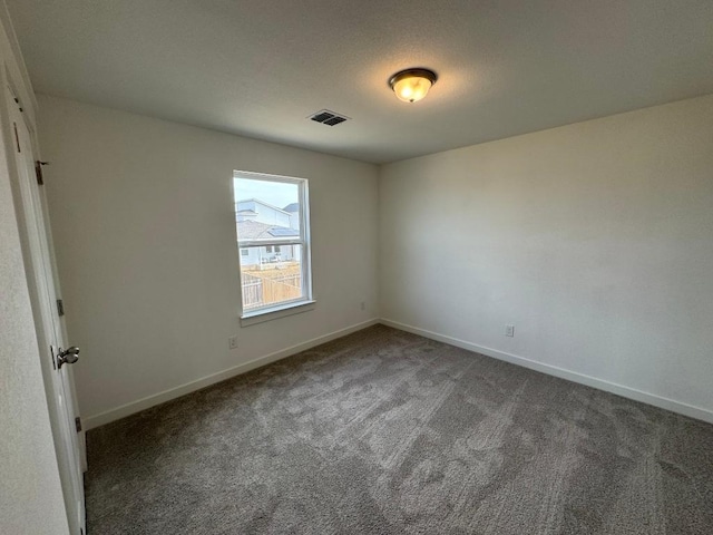 carpeted empty room with baseboards, visible vents, and a textured ceiling