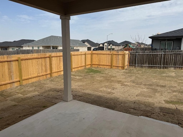 view of yard featuring a patio, a fenced backyard, and a residential view