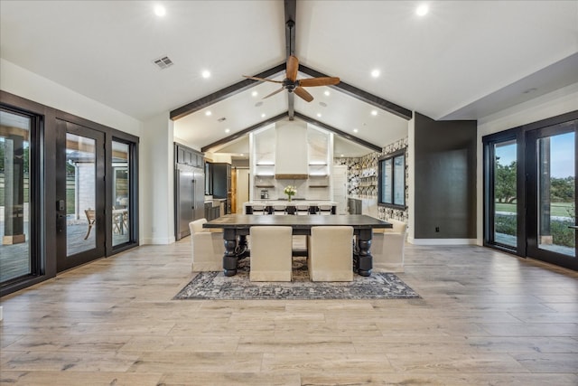 kitchen with ceiling fan, light hardwood / wood-style floors, beam ceiling, and a breakfast bar