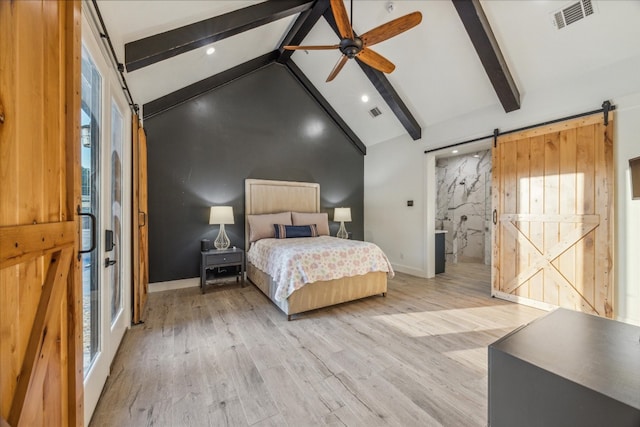 bedroom with a barn door, connected bathroom, beamed ceiling, light wood-type flooring, and ceiling fan