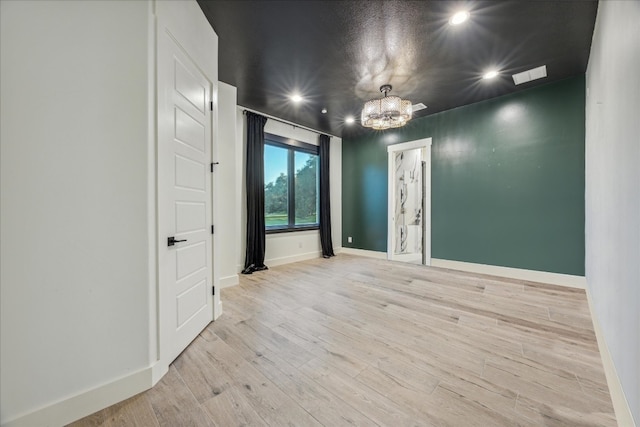 empty room featuring light hardwood / wood-style floors and an inviting chandelier