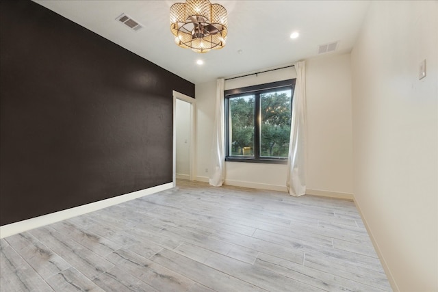 unfurnished room featuring light hardwood / wood-style flooring and a chandelier