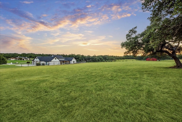 yard at dusk featuring a rural view