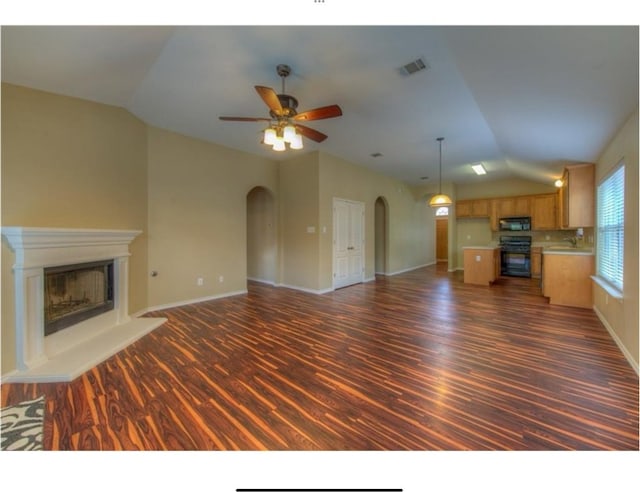 unfurnished living room featuring vaulted ceiling, ceiling fan, and dark wood-type flooring