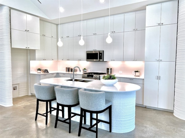 kitchen featuring white cabinets, a breakfast bar area, appliances with stainless steel finishes, decorative light fixtures, and sink