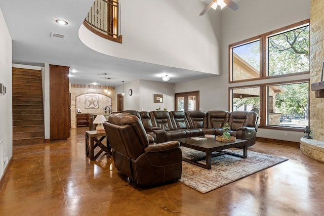 living room featuring a towering ceiling, ceiling fan, and concrete flooring