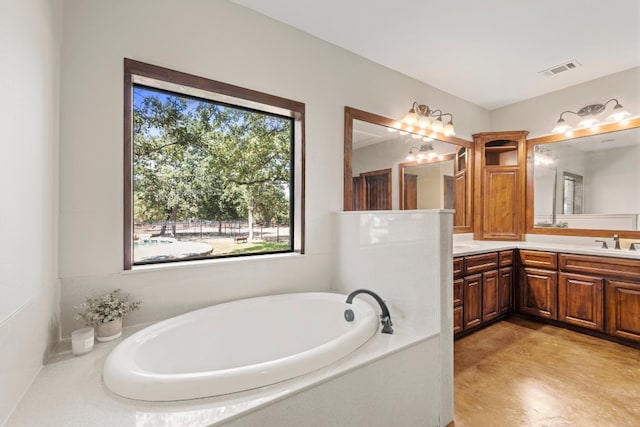 bathroom with vanity and tiled bath