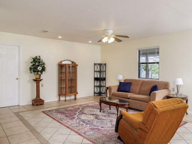 living room featuring ceiling fan, light tile patterned flooring, and a textured ceiling