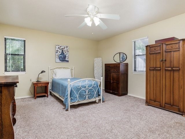 bedroom featuring light carpet, ceiling fan, and multiple windows