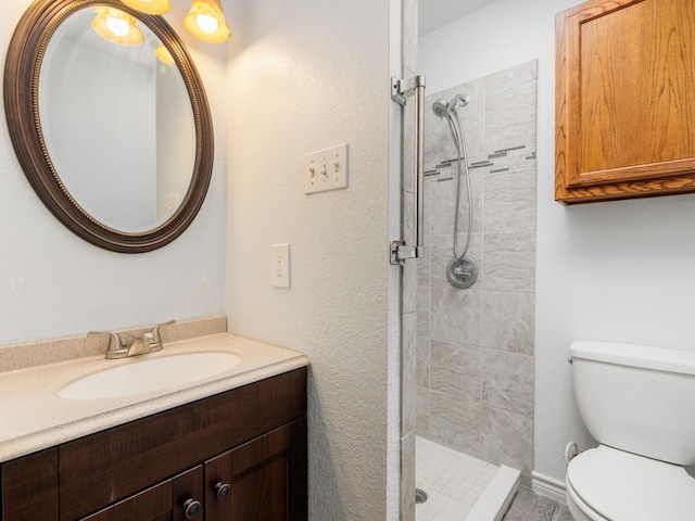 bathroom with a tile shower, vanity, and toilet